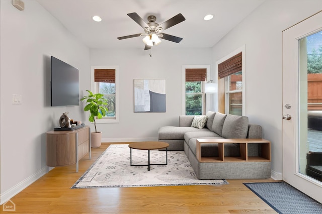 living room featuring light wood-type flooring, ceiling fan, and a healthy amount of sunlight