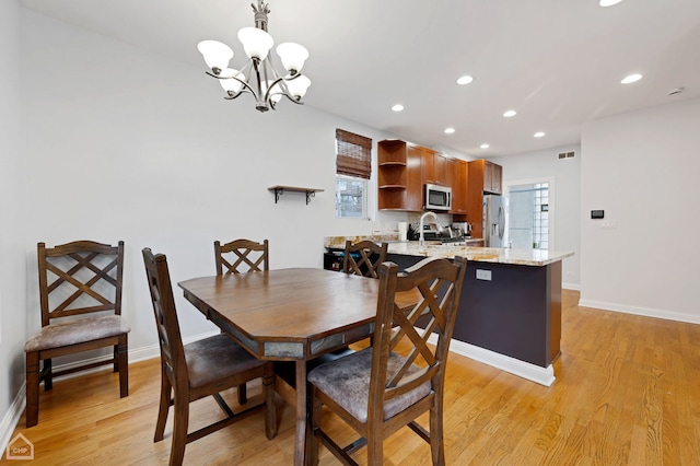 dining area featuring light wood-type flooring and a notable chandelier