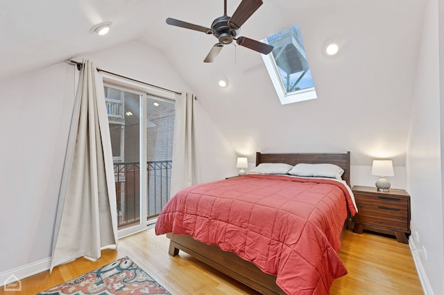 bedroom with access to exterior, light wood-type flooring, ceiling fan, and vaulted ceiling with skylight