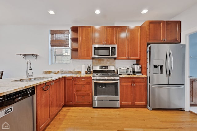 kitchen with appliances with stainless steel finishes, light hardwood / wood-style floors, tasteful backsplash, and sink