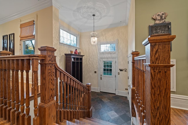 foyer entrance with ornamental molding and a chandelier