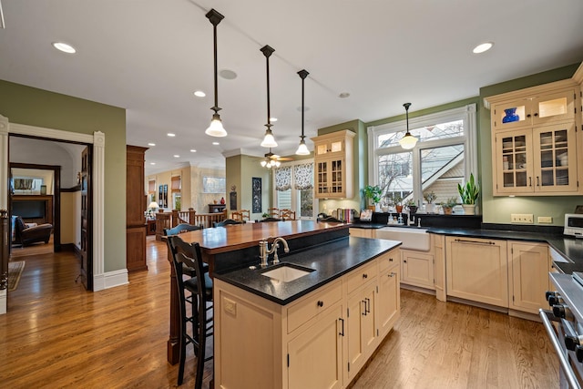 kitchen featuring decorative light fixtures, sink, high end stove, a breakfast bar, and a center island with sink