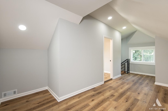 bonus room with hardwood / wood-style flooring and vaulted ceiling