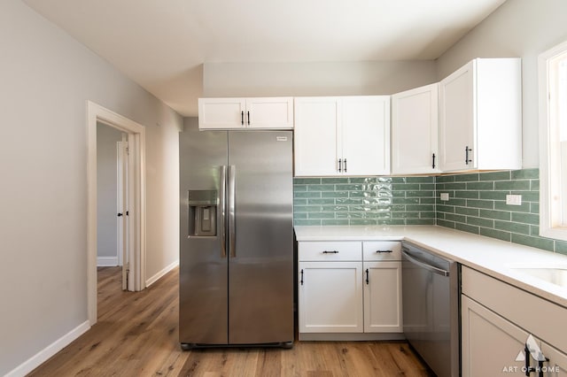 kitchen with decorative backsplash, white cabinetry, light wood-type flooring, and appliances with stainless steel finishes