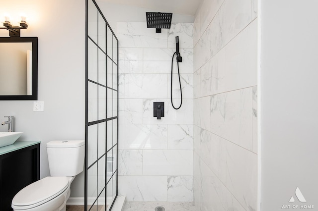 bathroom featuring vanity, toilet, and tiled shower