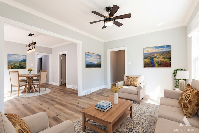 living room featuring ceiling fan with notable chandelier, light hardwood / wood-style floors, and ornamental molding