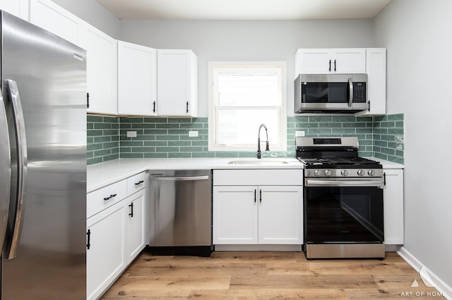 kitchen with white cabinets, light wood-type flooring, sink, and appliances with stainless steel finishes