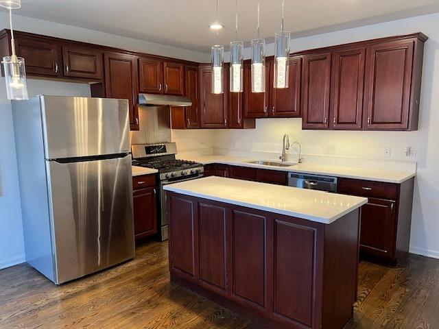 kitchen featuring pendant lighting, stainless steel appliances, a center island, and sink