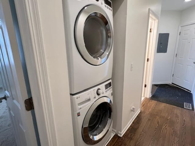 clothes washing area with stacked washer and clothes dryer, dark hardwood / wood-style floors, and electric panel