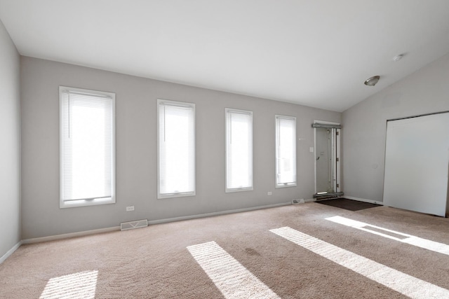 spare room featuring light carpet, plenty of natural light, and lofted ceiling