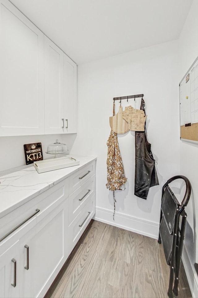 clothes washing area featuring cabinets, separate washer and dryer, and light hardwood / wood-style flooring