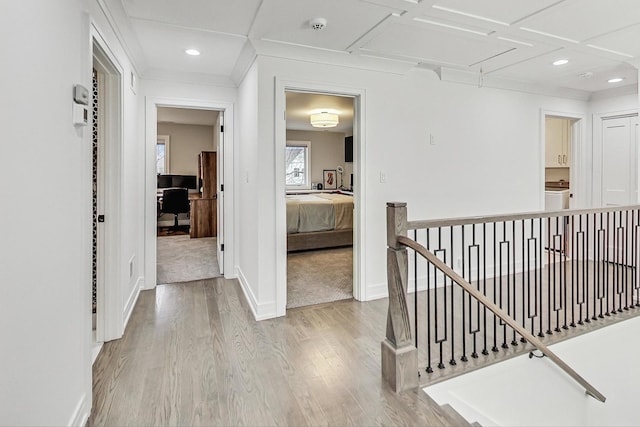 hall with light wood-type flooring, crown molding, and coffered ceiling