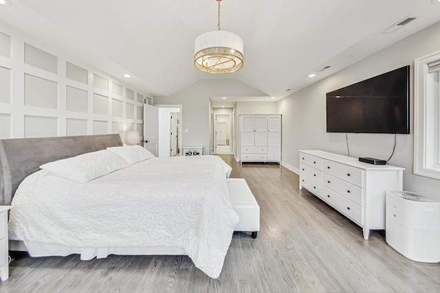 bedroom featuring vaulted ceiling, light hardwood / wood-style flooring, and connected bathroom