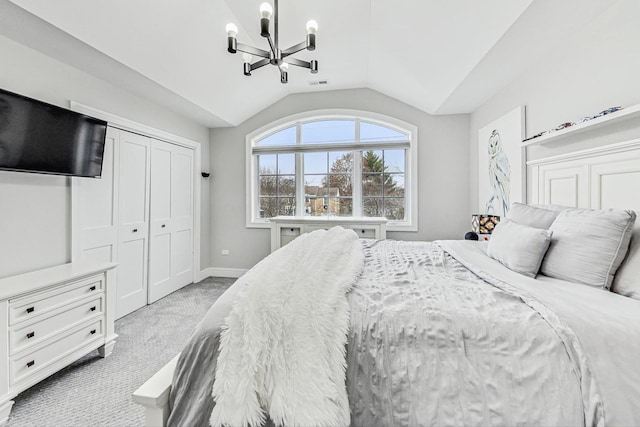 bedroom with a closet, light colored carpet, lofted ceiling, and a notable chandelier