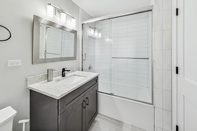 full bathroom featuring combined bath / shower with glass door, vanity, and toilet