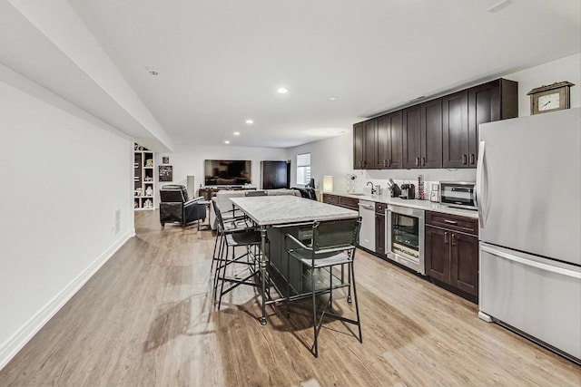 kitchen with a breakfast bar, appliances with stainless steel finishes, light hardwood / wood-style flooring, and dark brown cabinets