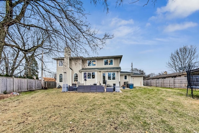 back of house featuring an outdoor living space, a trampoline, and a yard