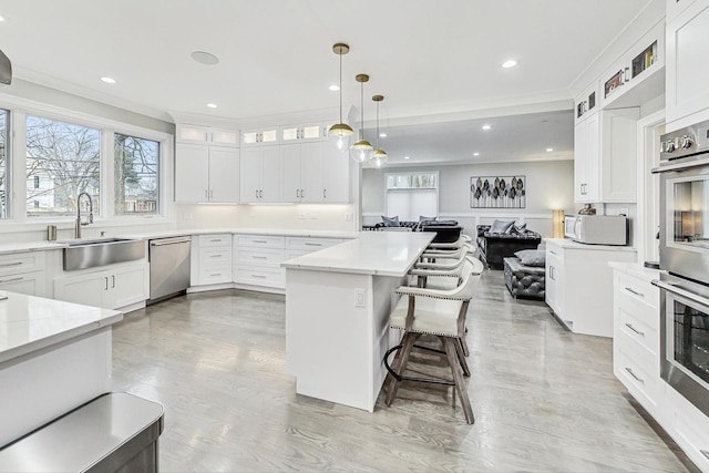 kitchen with sink, pendant lighting, a breakfast bar area, white cabinets, and appliances with stainless steel finishes