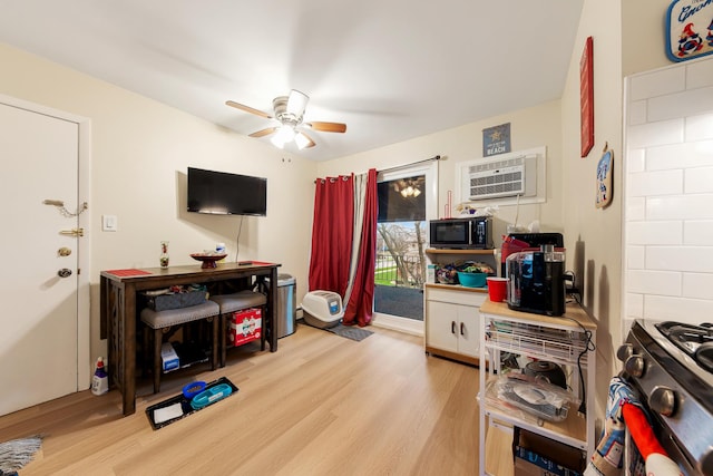 interior space with ceiling fan, a wall mounted AC, and light hardwood / wood-style flooring