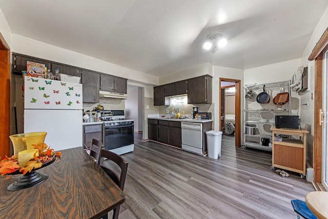 kitchen featuring sink, light hardwood / wood-style flooring, backsplash, white appliances, and dark brown cabinets