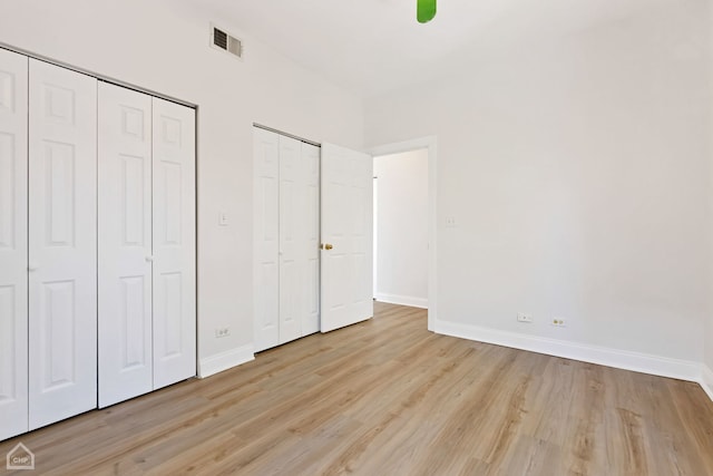 unfurnished bedroom featuring light wood-type flooring and multiple closets