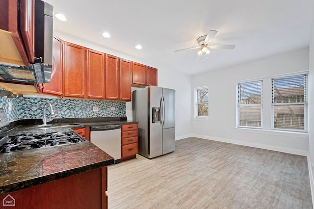 kitchen with sink, ceiling fan, dark stone countertops, appliances with stainless steel finishes, and tasteful backsplash