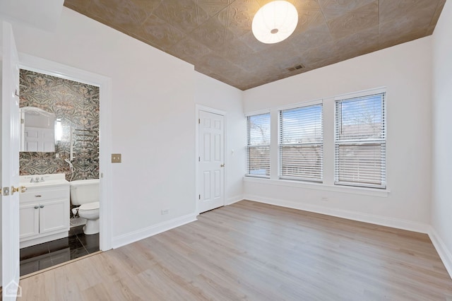 unfurnished bedroom featuring light wood-type flooring, sink, and connected bathroom