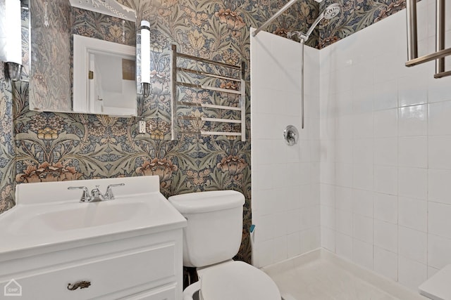 bathroom featuring vanity, toilet, and a tile shower