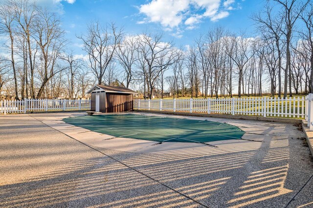 view of swimming pool featuring a patio area and a shed