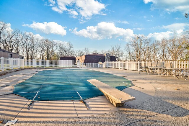 view of swimming pool with a diving board and a patio