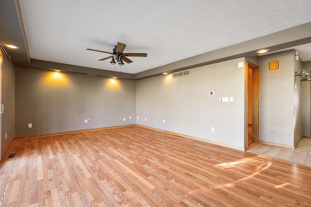 empty room with a textured ceiling, light hardwood / wood-style floors, and ceiling fan