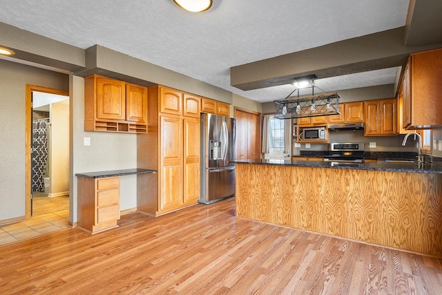 kitchen featuring kitchen peninsula, a textured ceiling, stainless steel appliances, sink, and light hardwood / wood-style floors