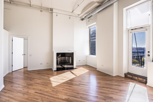 unfurnished living room with wood-type flooring and a towering ceiling