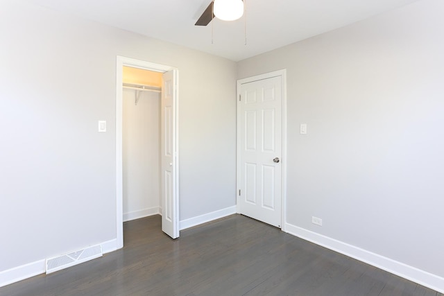 unfurnished bedroom featuring ceiling fan, dark hardwood / wood-style flooring, a spacious closet, and a closet