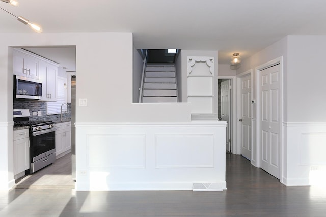 kitchen with sink, stainless steel appliances, tasteful backsplash, white cabinets, and hardwood / wood-style flooring