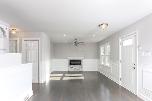 unfurnished living room featuring a fireplace, ceiling fan, and dark wood-type flooring