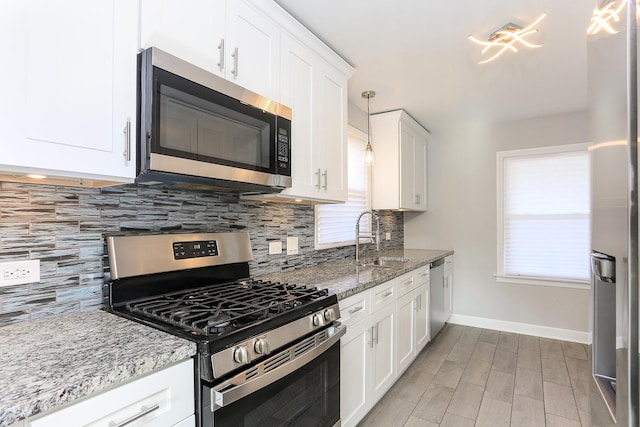 kitchen with white cabinets, sink, tasteful backsplash, decorative light fixtures, and stainless steel appliances