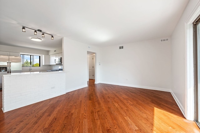 unfurnished living room with light wood-type flooring and rail lighting