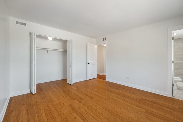 unfurnished bedroom with connected bathroom, a closet, and light wood-type flooring