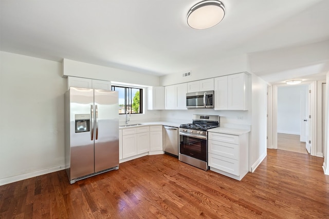 kitchen with hardwood / wood-style flooring, white cabinetry, sink, and appliances with stainless steel finishes