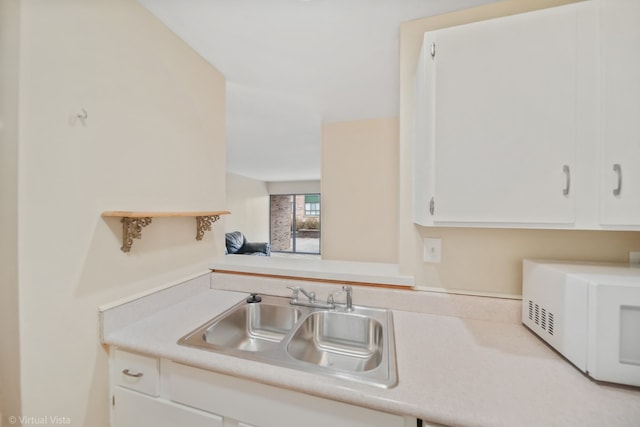 1926 Prairie Sq Unit 103, Schaumburg, IL 60173 - kitchen with white microwave, a sink, light countertops, and white cabinetry