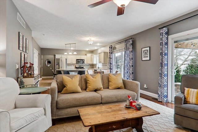 living room featuring ceiling fan, light wood-type flooring, and sink