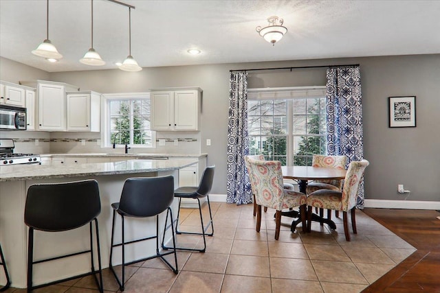 kitchen with decorative light fixtures, white cabinetry, sink, and light hardwood / wood-style flooring