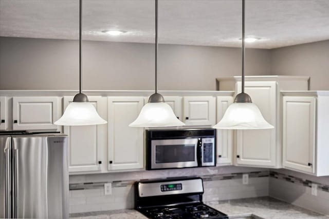 kitchen featuring white cabinets, pendant lighting, and appliances with stainless steel finishes