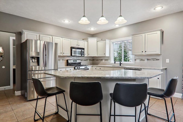 kitchen featuring white cabinets, appliances with stainless steel finishes, a kitchen island, and sink