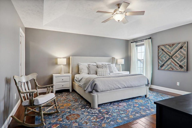 bedroom with a textured ceiling, ceiling fan, and dark hardwood / wood-style floors