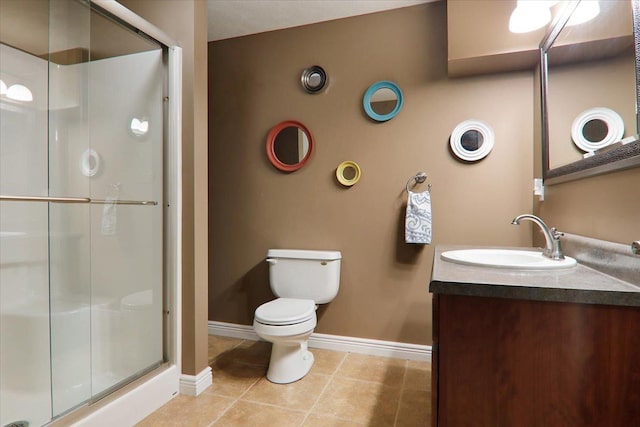 bathroom featuring toilet, vanity, tile patterned floors, and a shower with door