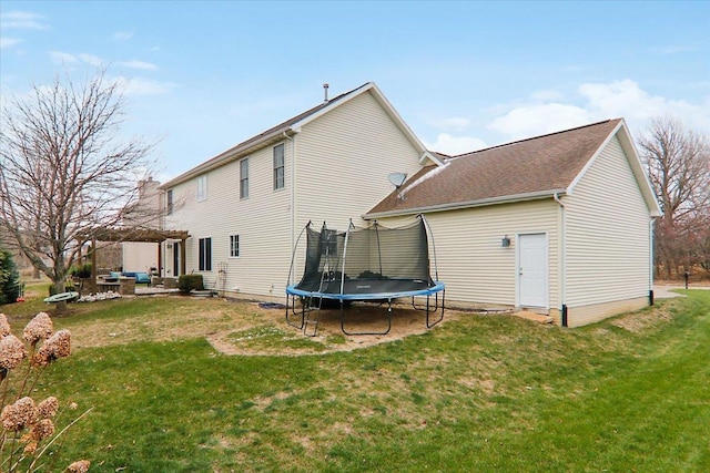 back of property with a lawn and a trampoline