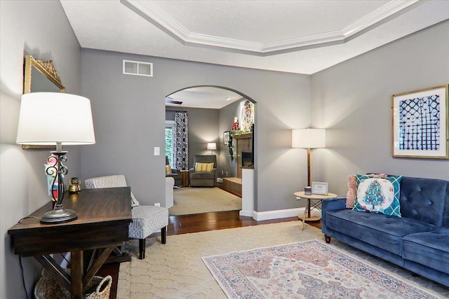 living room with a tray ceiling, ornamental molding, and hardwood / wood-style flooring