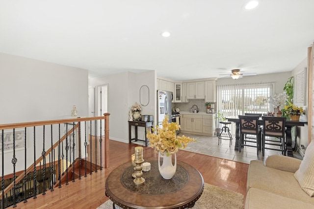 living room with ceiling fan, sink, and light wood-type flooring